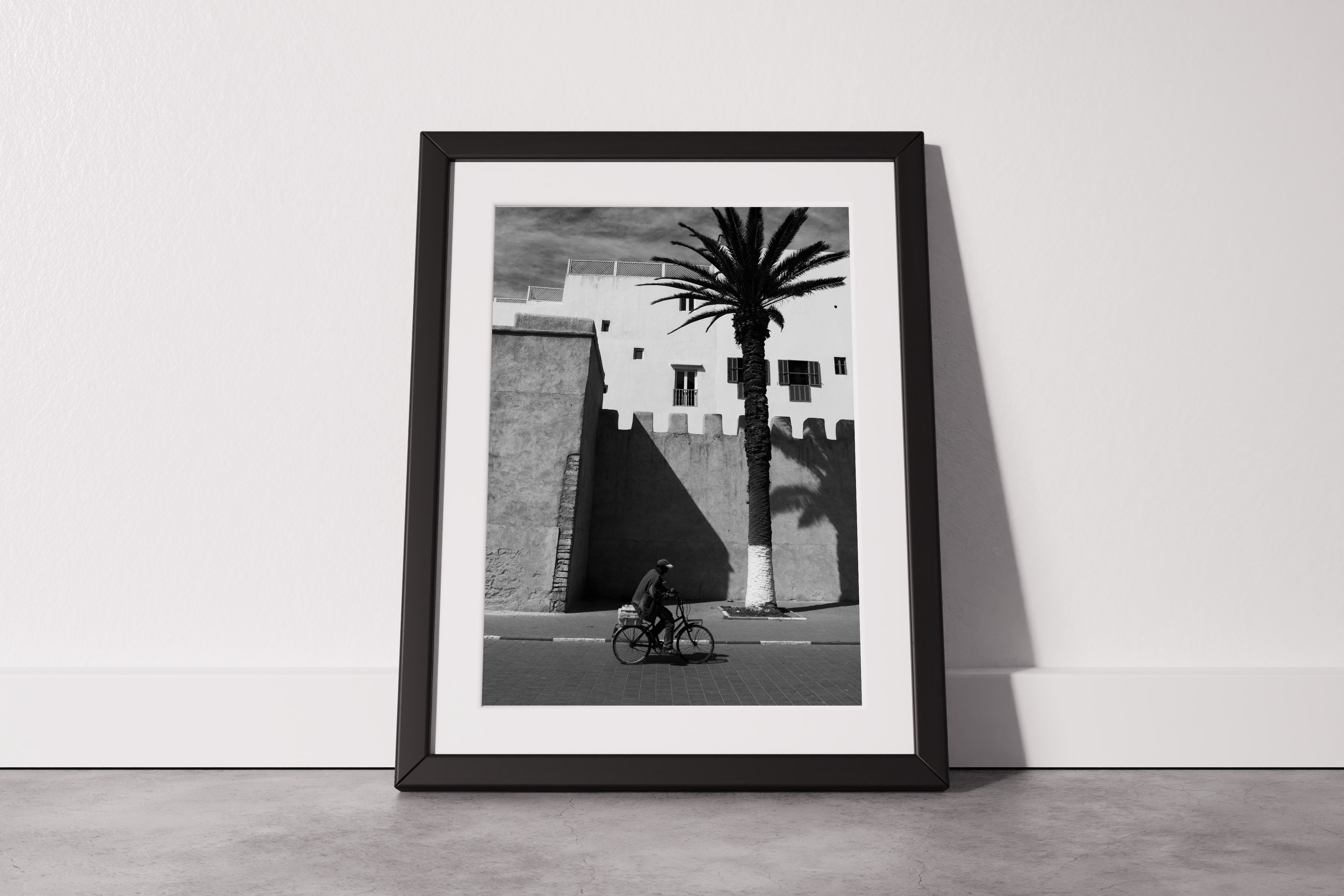 A Man on a Bicycle in Morocco, with a Palm Tree and traditional architecture - Black & White Photography Print A1 A2 A3 - Explura.co