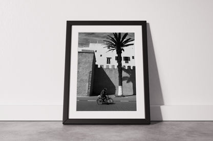 A Man on a Bicycle in Morocco, with a Palm Tree and traditional architecture - Black & White Photography Print A1 A2 A3 - Explura.co
